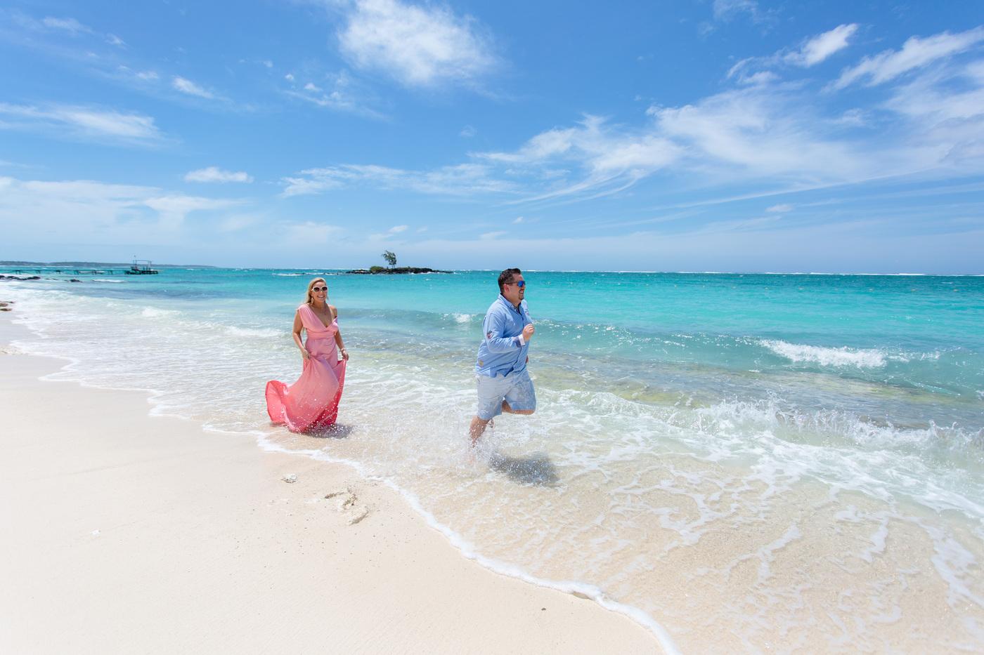 Couple running along white sand beach mauritius