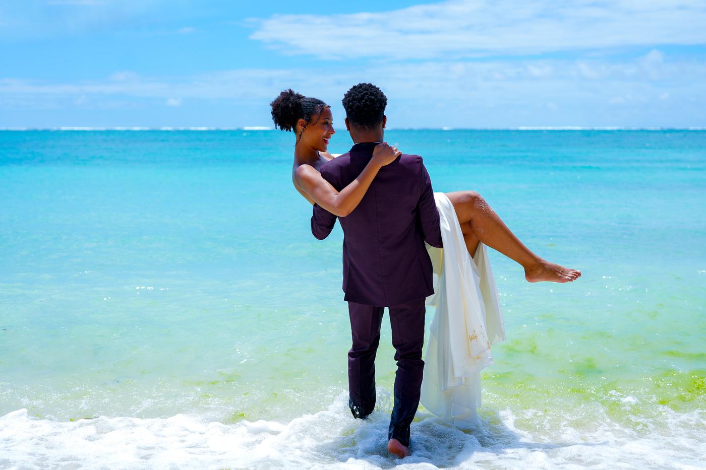 Groom carrying bride shallow tropical water mauritius